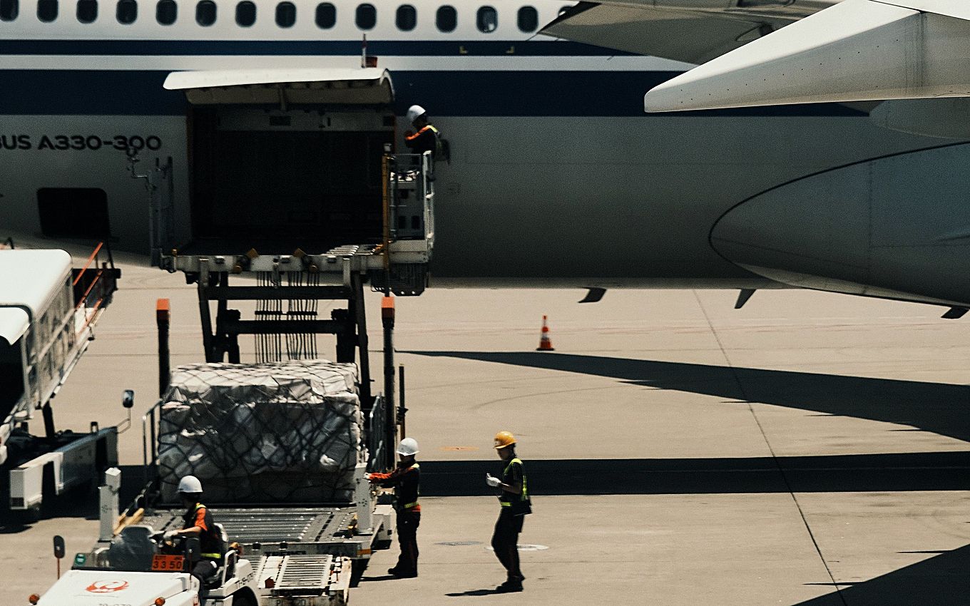A netted air cargo pallet raised on a main-deck loader into an aircraft hold